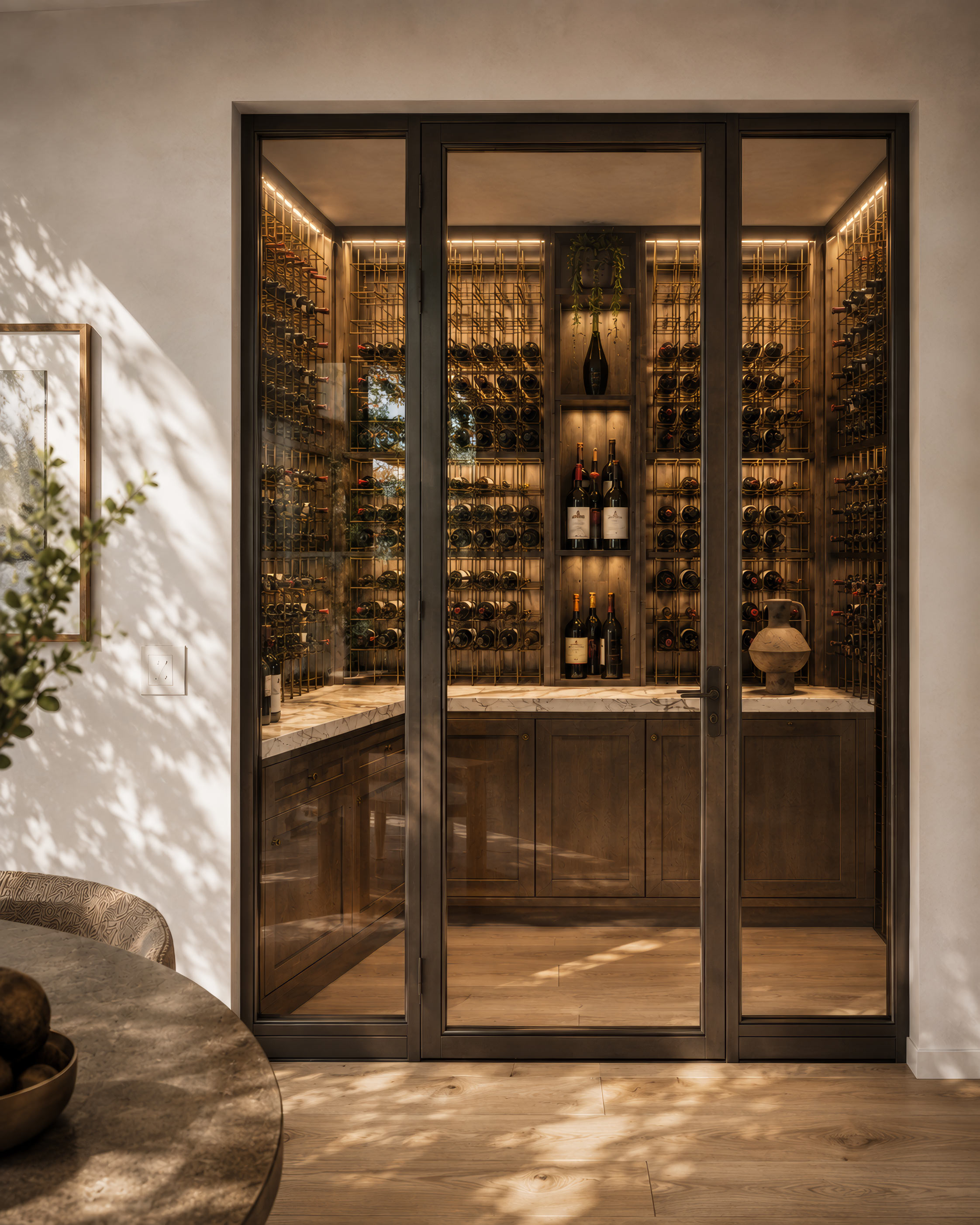 Glass-enclosed wine bar with illuminated bottle racks and custom cabinetry